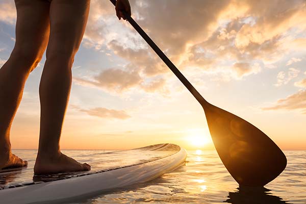 Holding SUP Paddle riding SUP looking at sunset